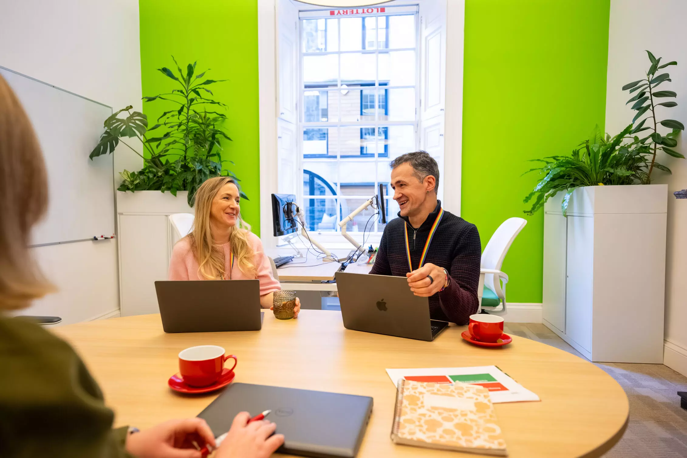 Marketing Employees outside. sitting on a wall, holding gold cheques