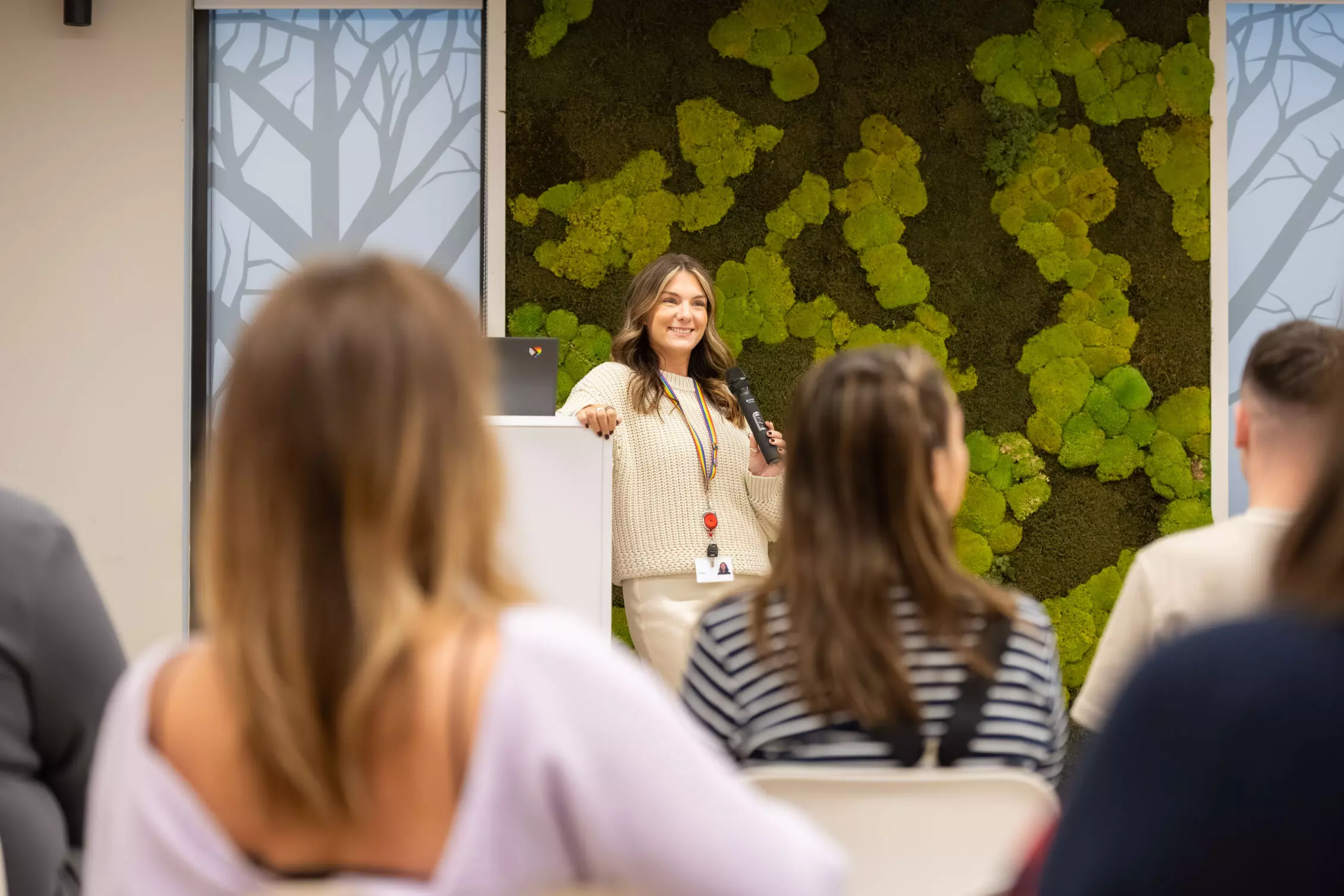 Marketing Employees outside. sitting on a wall, holding gold cheques
