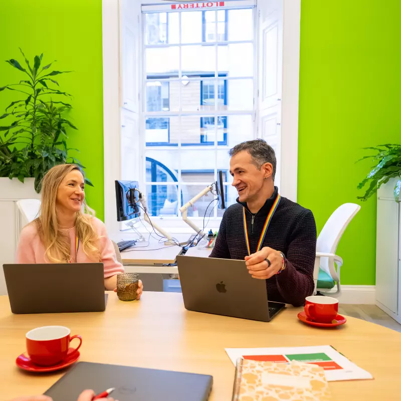 Two employee's sitting at desk with their laptops