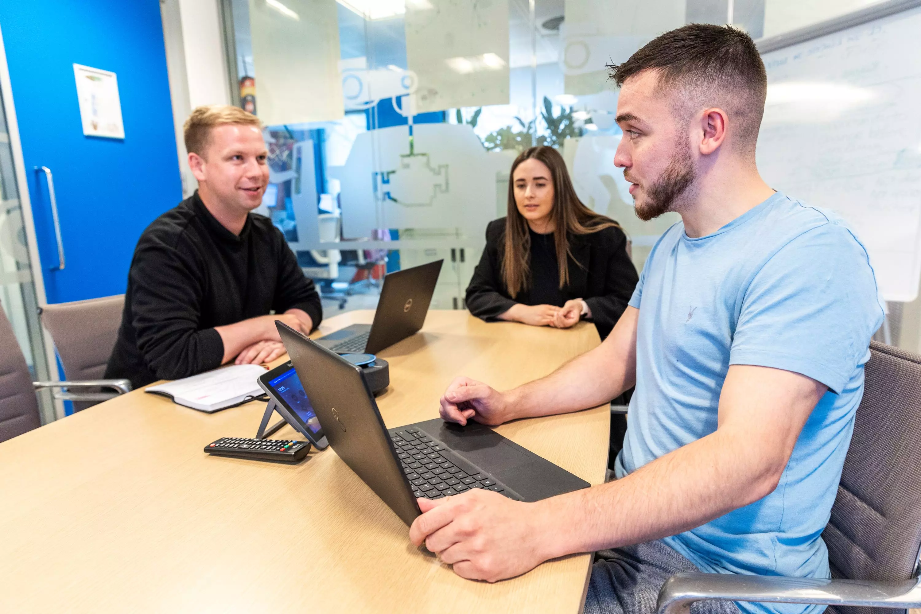 Tech A group of employees sitting around a table in an office meeting room.